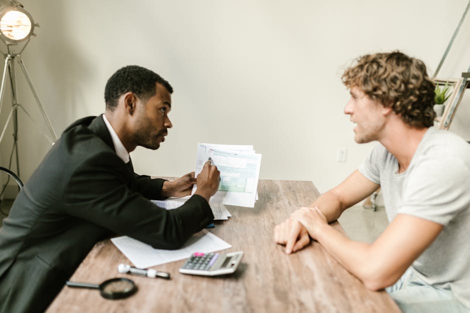 A financial advisor discusses paperwork with a client at a desk in a modern office